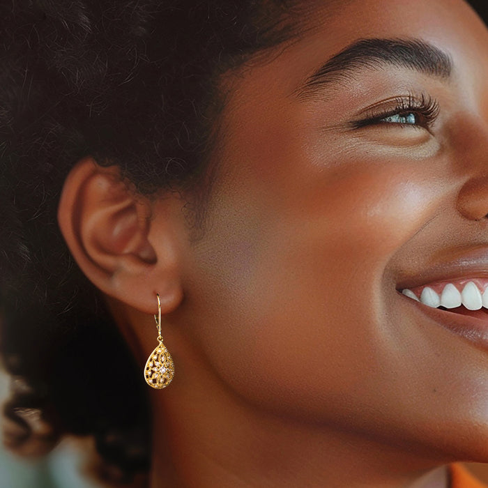 Woman wearing gold teardrop openwork diamond leverback earrings