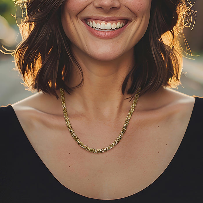 Gold-tone Byzantine chain necklace with interlaced links, worn at the collarbone