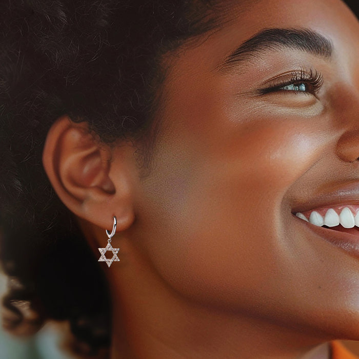 Sterling silver hoop earrings with Star of David dangling charm, worn on ear