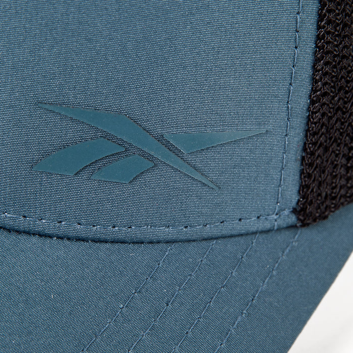 Close-up of the Reebok Athletic Cap in blue, highlighting the front left logo, moisture-wicking sweatband, visible stitching, and black mesh side section.
