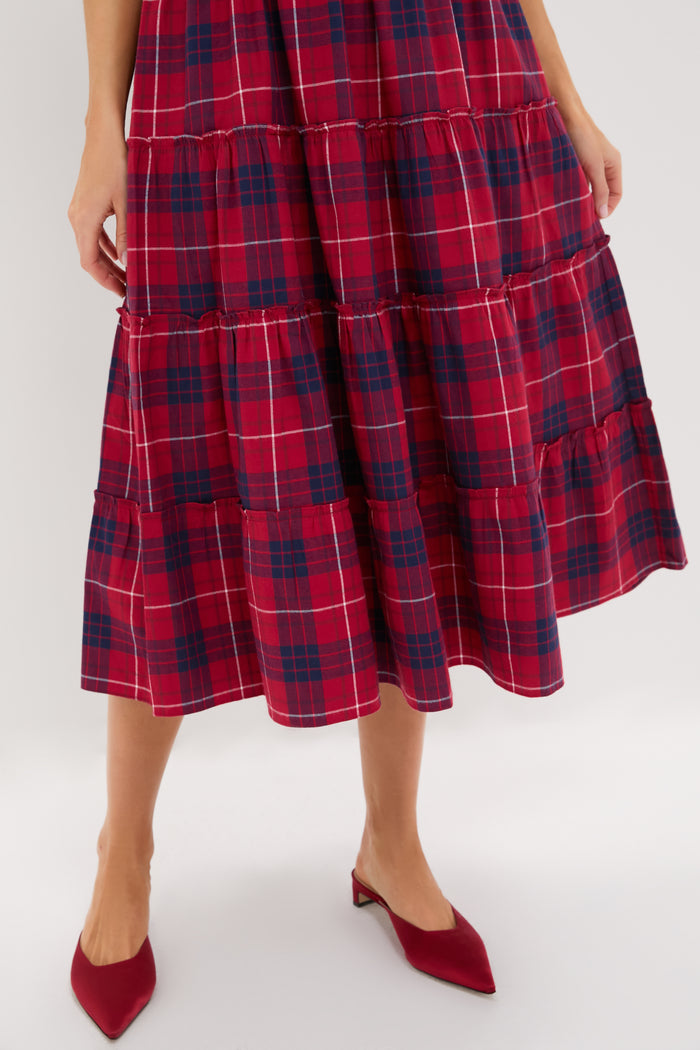 A person wearing a Hill House Home red and navy plaid A-line midi skirt with red pointed low-heeled shoes stands against a plain background.