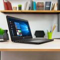 A Dell Latitude 3300 i5 8250U 16GB 256GB SSD 13.3 Windows 11 Pro laptop sits on a desk in a tidy office with shelves, books, and stationery visible in the background.
