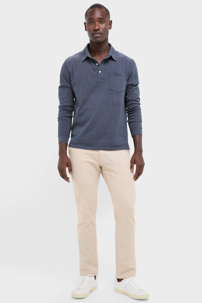 Man models the Faded Navy Garment Dyed Long Sleeve Polo, showcasing its classic, effortless style with a relaxed pose, epitomizing high-end, fun fashion.