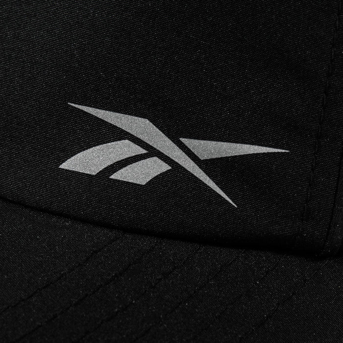 Close-up of a black Reebok Flow Piped Cap with a silver logo on the front and a moisture-wicking sweatband for all-day comfort.