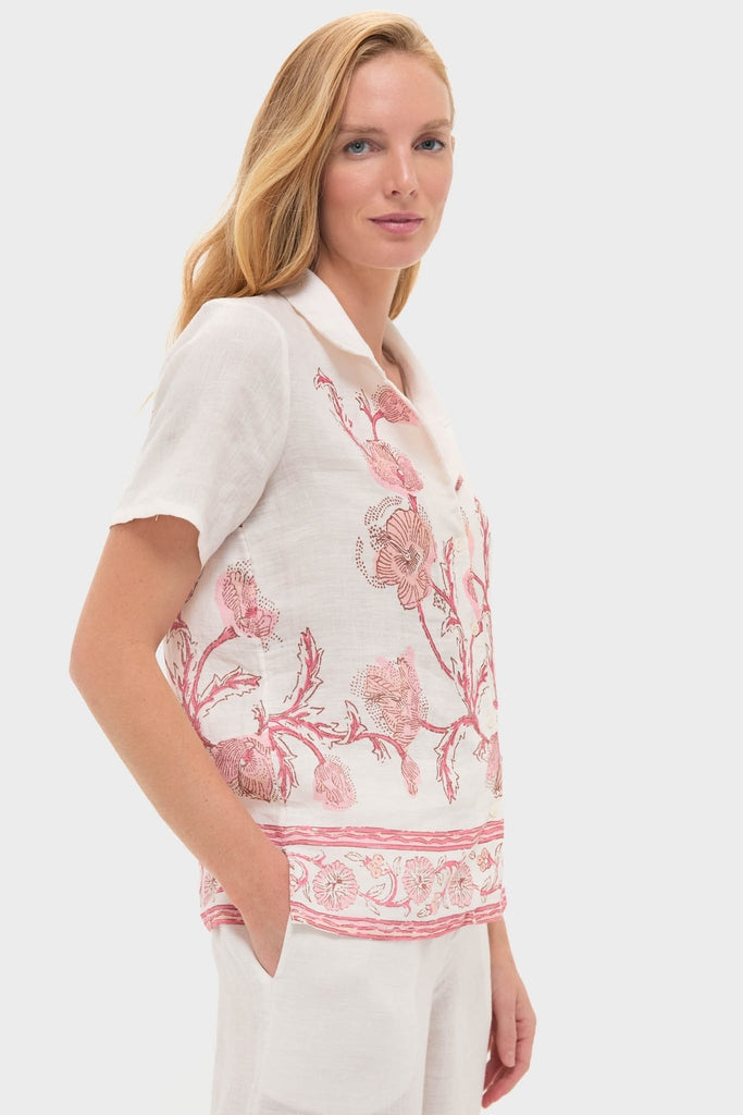 Model wearing the Hibiscus Bloom Pink Gabriella Shirt, a classic, effortless white linen top with intricate pink floral embroidery and hand-stitched trim, exuding a fun, high-end style.