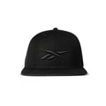The Reebok Identity Vector Cap is a black snapback hat with a flat brim and adjustable closure, featuring an embroidered black Reebok logo on the front, shown against a white background.