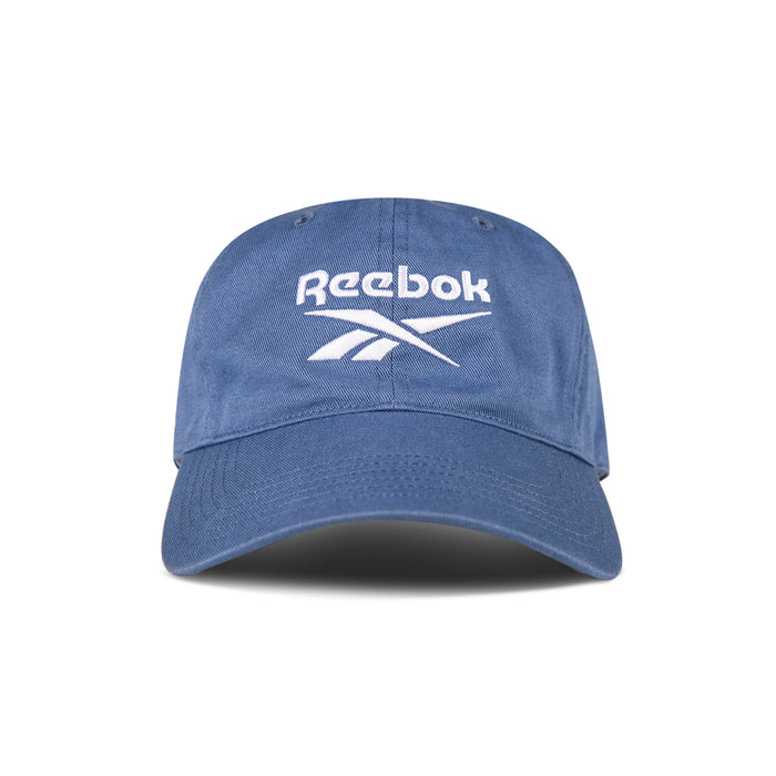 The Reebok Logo Cap features a curved brim and front white logo embroidery. Made from cotton twill with an adjustable buckle for comfort, this cap is shown against a white background.