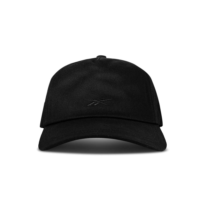 The Reebok Logo S-Vector Cap is a plain black cotton twill snapback with a curved brim and subtle black logo embroidery on the front center, shown in the photograph from the front against a white background.