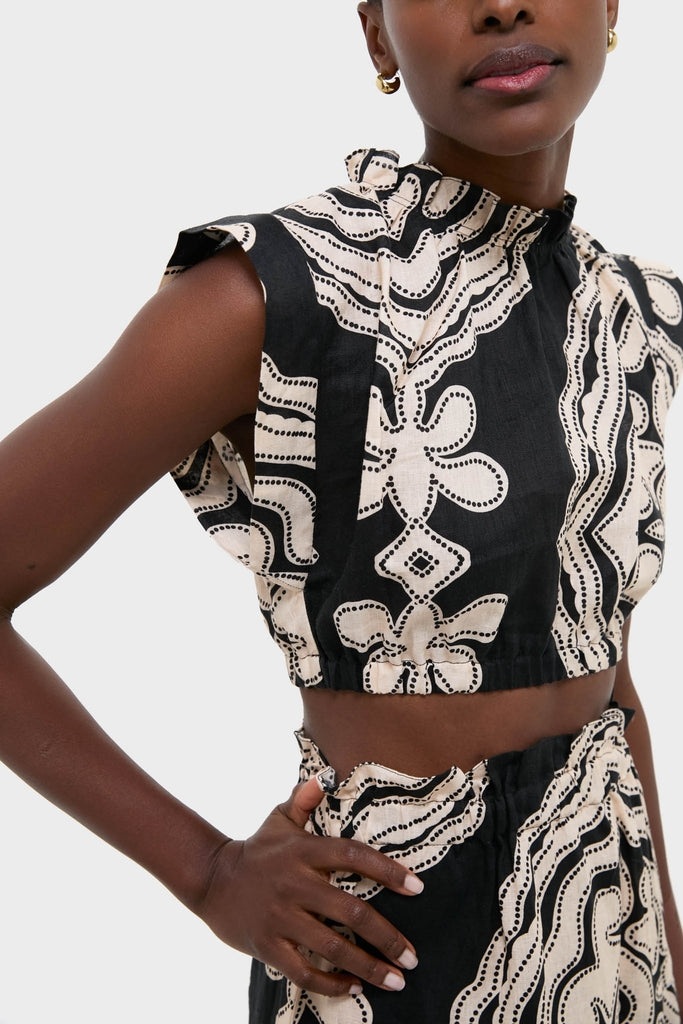 Model wearing Niku Black Muna Ruched Crop Top showcases an effortless, high-end look with a classic abstract pattern, ruched neckline, and elegant gold hoop earrings.