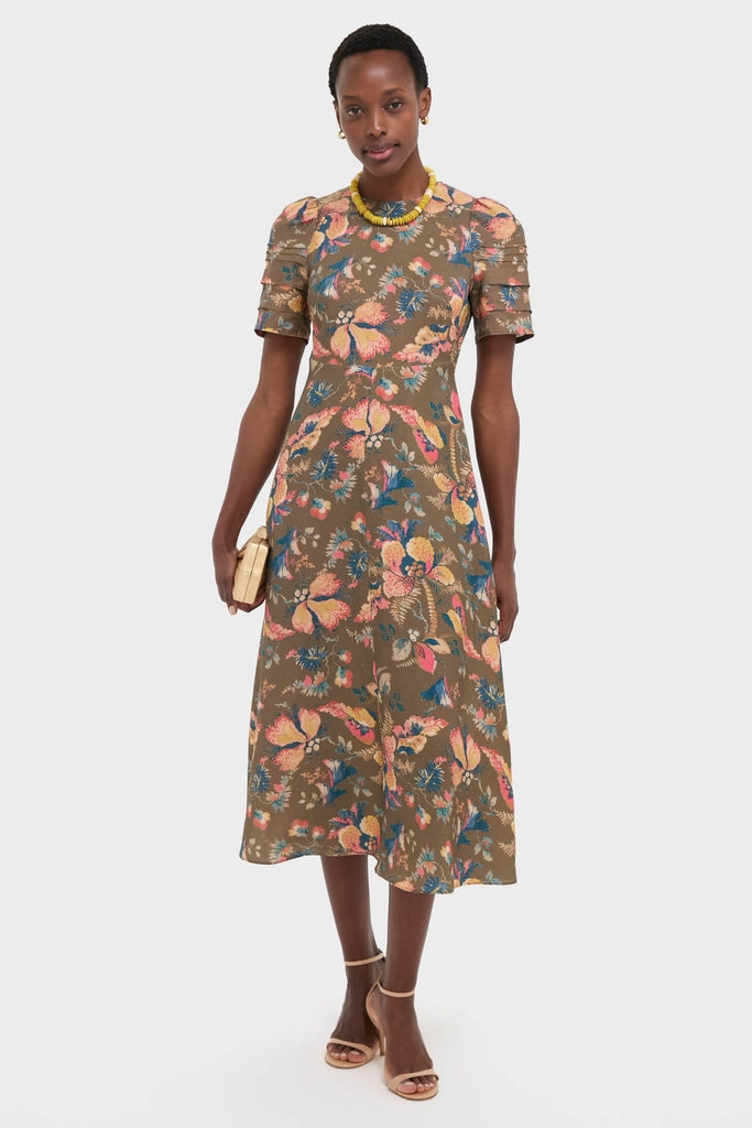 Woman in the Olive Floral Casey Dress, featuring an effortless, classic multicolor floral print, tiered sleeves, and a fun, high-end style, accessorized with a beaded necklace and clutch.