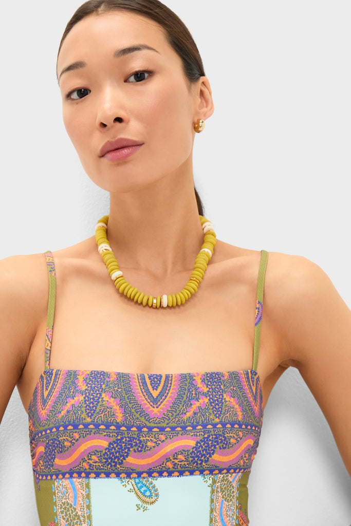 Woman in a classic, multicolored Pastel Patchwork Lucent One Piece, effortlessly styled with a chunky necklace, embodies Tuckernuck's fun and high-end bohemian spirit.