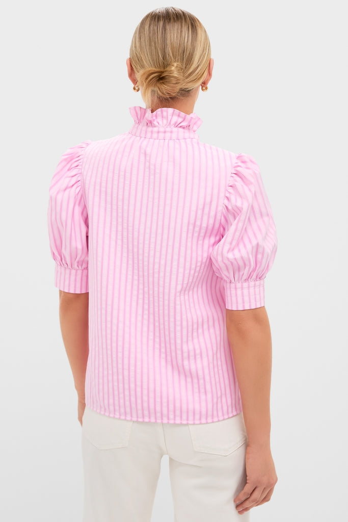 Back view of a woman wearing the classic Pink Candy Stripe Louisa Blouse with a ruffled mock-neck and puffed sleeves, paired effortlessly with off-white pants.