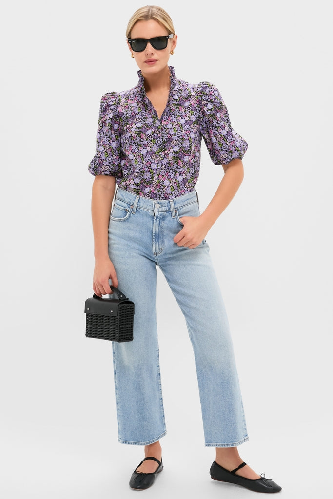 Woman models the Shades of Purple Floral Florence Blouse, a classic, fun, short-sleeved top with ruffled collar and puffed sleeves, capturing Tuckernuck's effortless, high-end style.