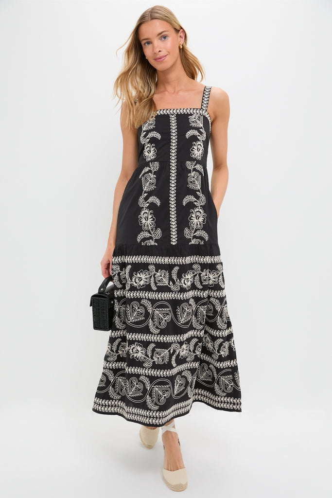 Model in Sweetheart Rio Dress, a classic black sundress with floral embroidery, paired with a black wicker handbag and espadrille wedges for an effortless, high-end look.