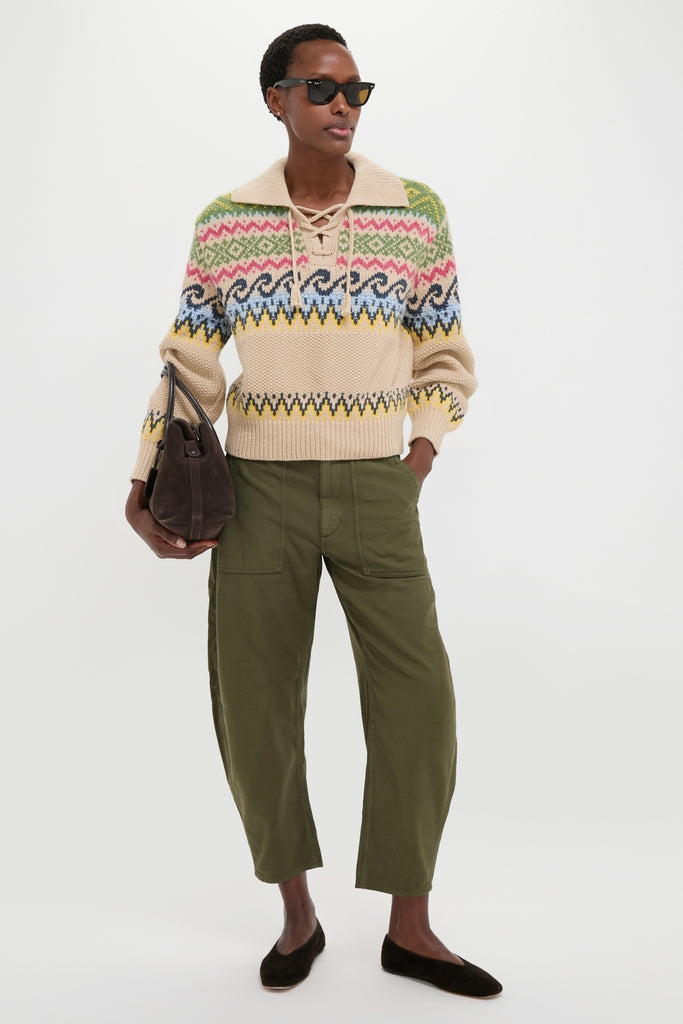 Model wearing Tan Multi Cotton Wool Blend Long Sleeve Tie Pullover, featuring classic Fair Isle motifs, paired with olive utility trousers and holding a suede handbag, embodying effortless, high-end style.