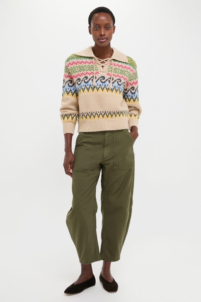 Woman in a classic, high-end Tan Multi Cotton Wool Blend Long Sleeve Tie Pullover, paired with effortless olive-green cropped trousers and dark flat shoes, embodying fun and timeless style.