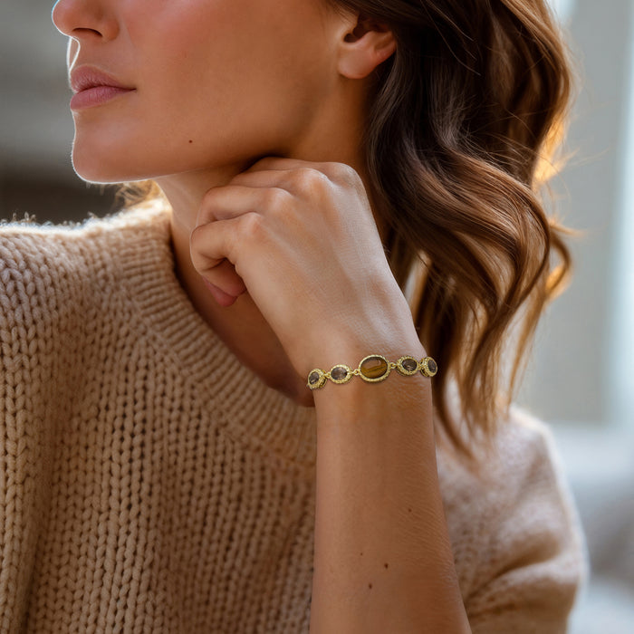 Gold bolo bracelet with oval tiger-eye and smoky quartz stones on wrist